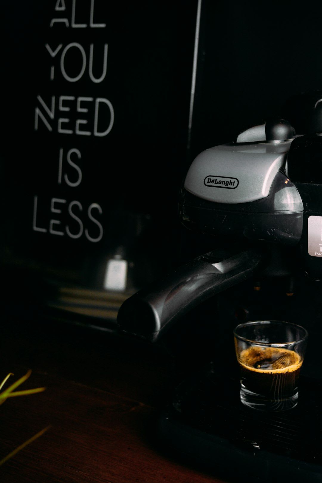 Eine Espressomaschine von DeLonghi mit einem Glas Espresso vor einem Schriftzug an der Wand. | Foto: Amr Taha™