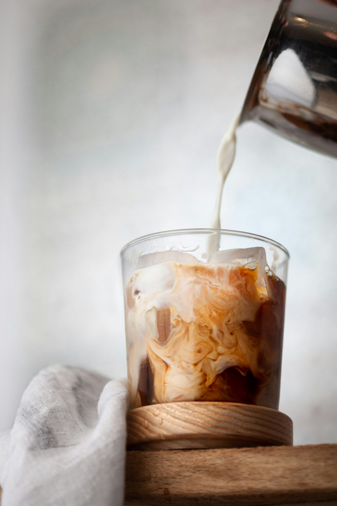 Ein erfrischendes Iced Coffee Rezept als sommerliches Kaffeegetränk in einem hohen Glas mit Eiswürfeln auf einer Terrasse. | Foto: Empreinte