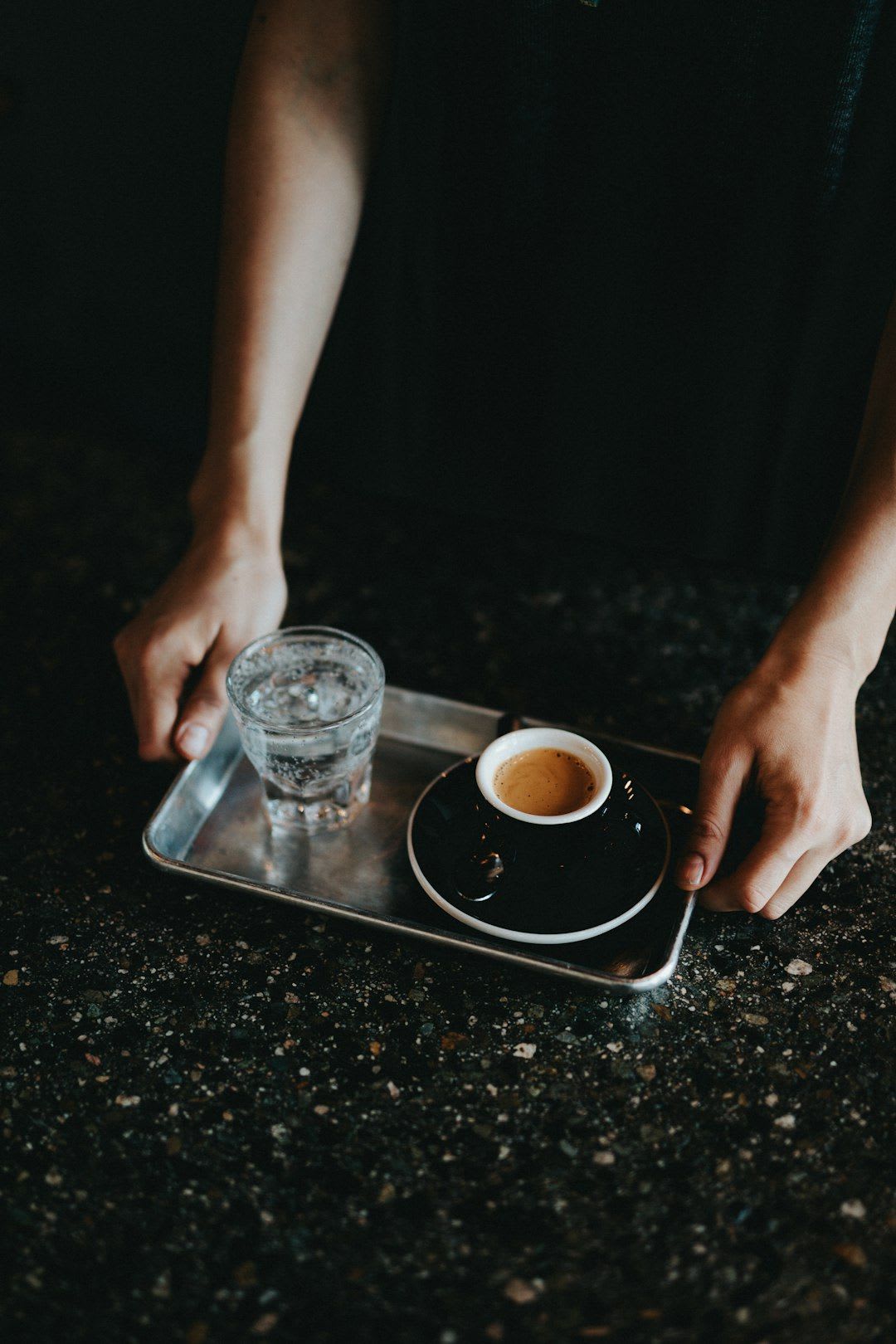 Eine Person legt eine Reinigungstablette in einen Jura Kaffeevollautomaten, dessen Display das Reinigungsprogramm anzeigt. | Foto: Nathan Dumlao