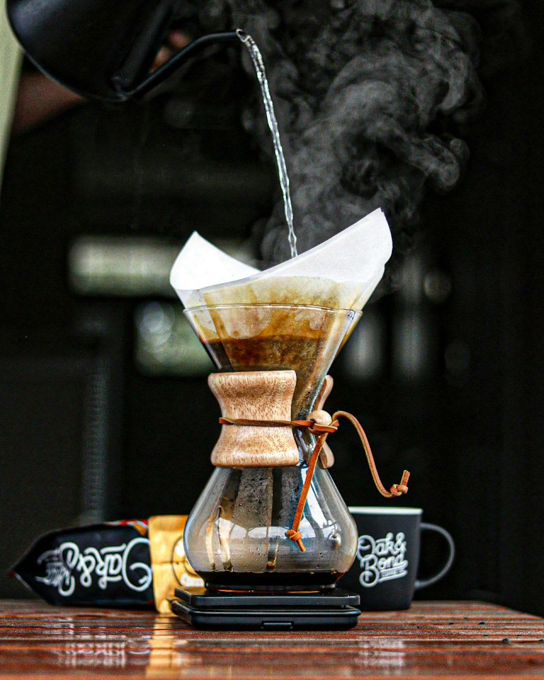 Draufsicht auf eine Kapselkaffeemaschine mit Milchaufschäumer, umgeben von Kaffeebohnen und Milch, warme Farbpalette, weiche Studiobeleuchtung | Foto: Oak & Bond Coffee Co.