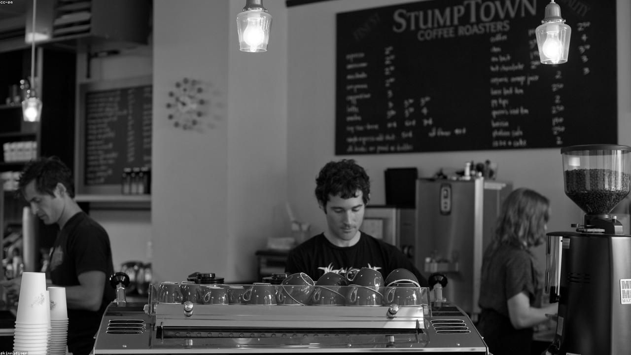 Barista reinigt den Brühkopf einer Espressomaschine mit einer Bürste